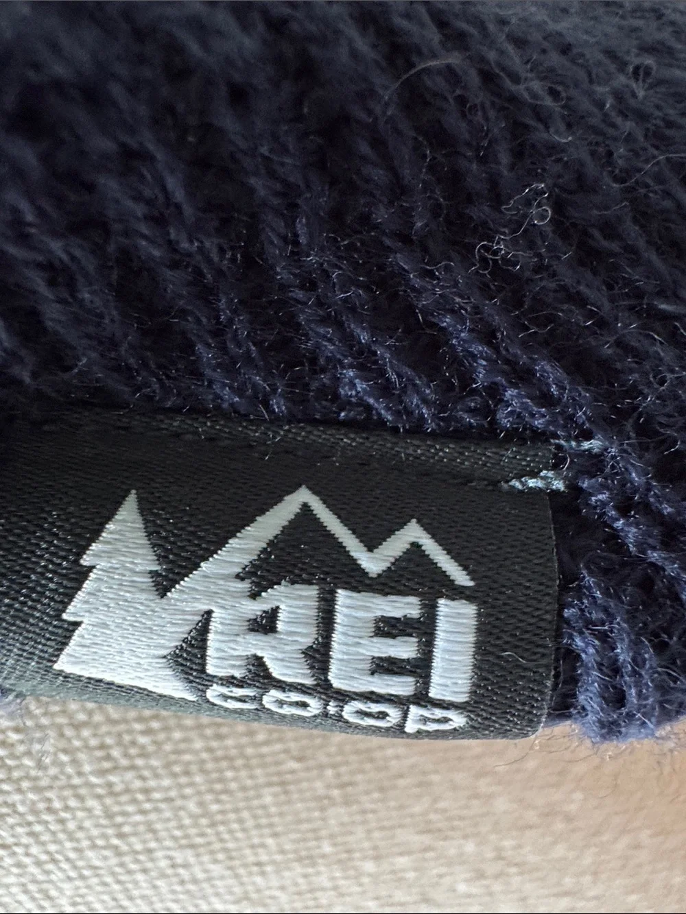 Kids REI acrylic knit beanie hat with pompom and ear flaps.